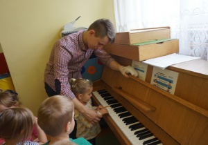 Oliwia z pomocą pana Karola podejmuje próbę gry na pianinie
